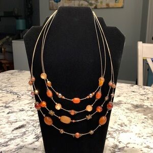 Four strand gold toned wire necklace w/ amber colored beads& lobster claw clasp.